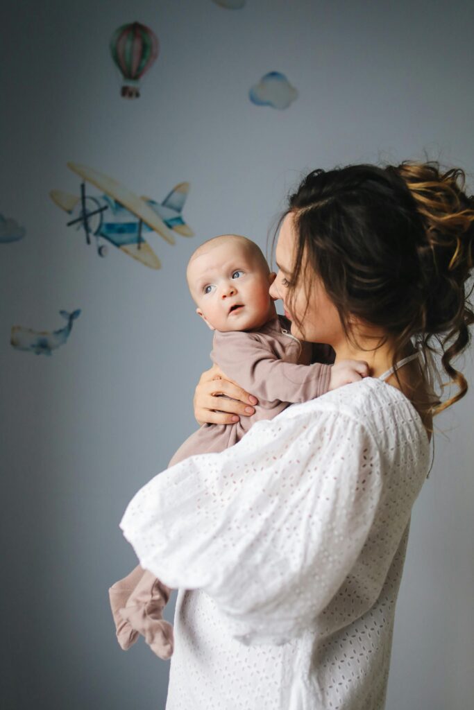 pexels-photo-3875218-3875218 A mother lovingly holds her baby in a nursery decorated with airplanes.
